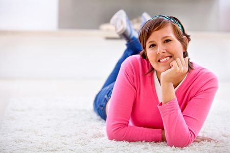 Happy casual woman lying on the carpet