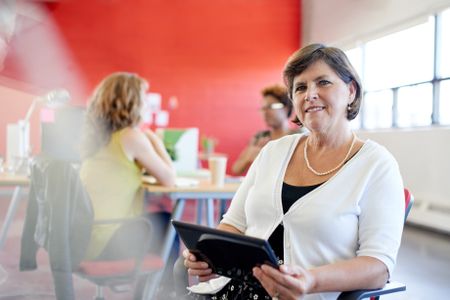 Confident female designer working on a digital tablet in red creative office space