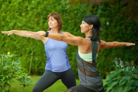 Two mature women keeping fit by doing yoga in the summer