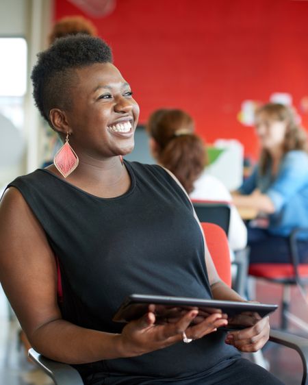 Confident female designer working on a digital tablet in red creative office space