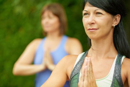 Two mature women keeping fit by doing yoga in the summer