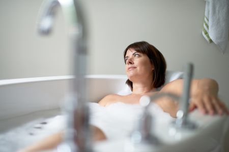 serene-mature-woman-looking-away-bathtub-386304985 Serene mature woman looking away in a bathtub