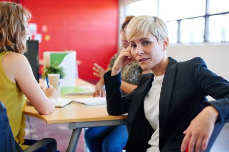 Confident female designer sitting at her desk for a brainstorming in red creative office space