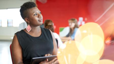 Confident female designer working on a digital tablet in red creative office space