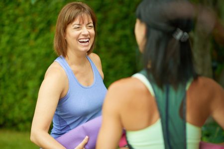 Two mature women talking before doing yoga in the summer