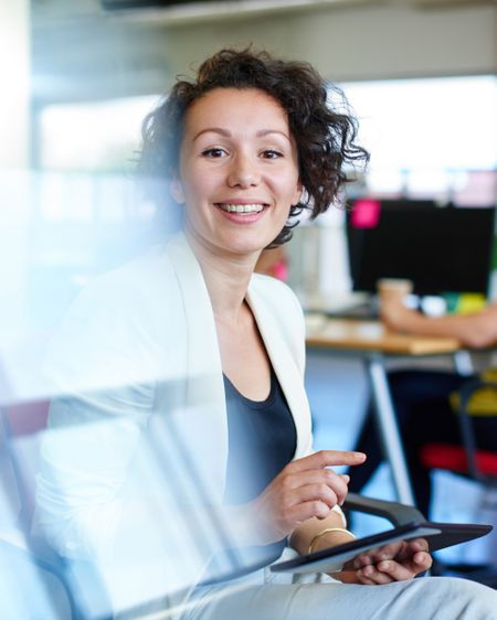 Confident female designer working on a digital tablet in red creative office space