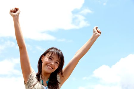 Excited woman portrait with arms raised outdoors