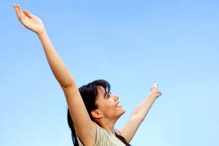 Excited woman portrait with arms raised outdoors