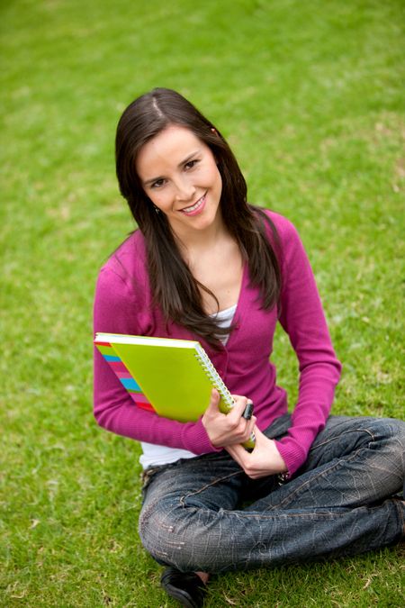 Beautiful female student sitting outdoors with a notebook
