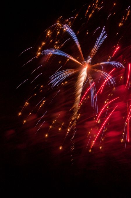 Red, white and blue burst of fireworks amid falling embers and red smoke