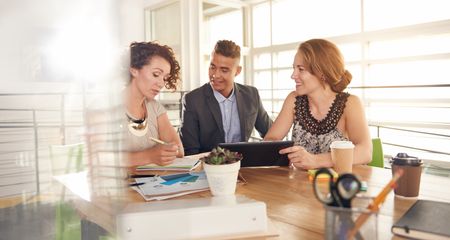 Image of three succesful business people using a tablet during at meeting