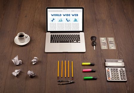 Laptop computer on wooden desk with office suplies