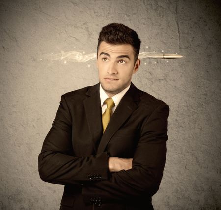 An elegant handsome business guy standing in front of wall with a bullet going through his head, making facial expressions concept