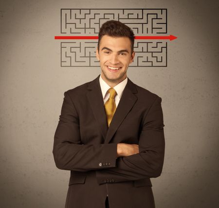 A young handsome business person making facial expression and solving maze with red arrow in front of clear, empty concrete wall background concept