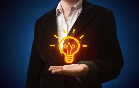 A creative businessman has a great bright idea illustrated by holding a drawn light bulb in the hand concept