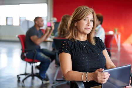 Confident female designer working on a digital tablet in red creative office space