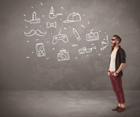 A funny hipster person in casual urban clothing shouting drawn everyday items like camera, tie or pen on city wall concept