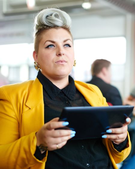 Confident and edgy female designer working on a digital tablet in red creative office space