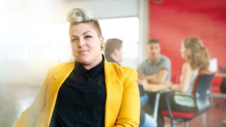 Confident and edgy female designer working on a digital tablet in red creative office space