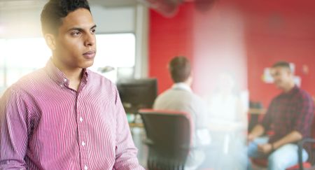 Confident male designer working on a digital tablet in red creative office space