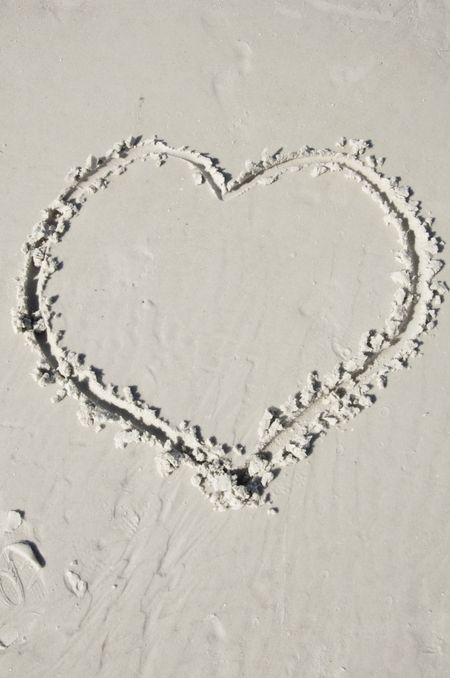 Human heart drawn in damp sand in afternoon sunlight