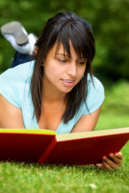 Girl portrait reading a book and smiling outdoors