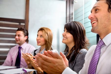 Business group at a meeting applauding and smiling