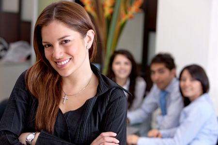 Business woman smiling in an office with her team behind her