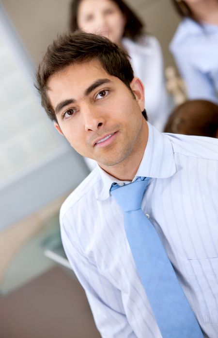business man portrait in an office with his team behind