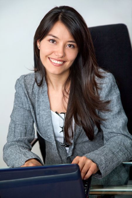 business woman on a laptop in an office smiling