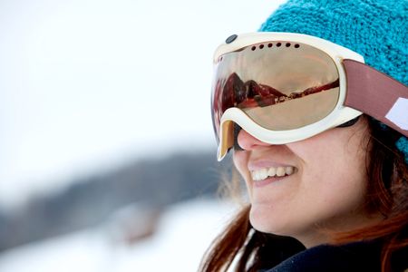 female skier smiling and wearing ski glasses in the mountains