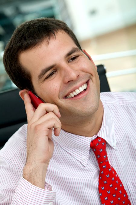 business man smiling and talking on a mobile phone in an office