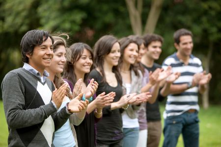 Group of people applauding and smiling outdoors