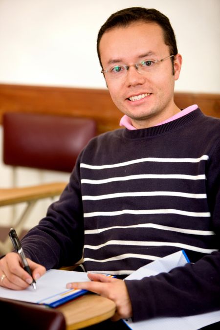 Male student with a notebook smiling indoors