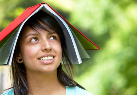 girl with a notebook on her head outdoors