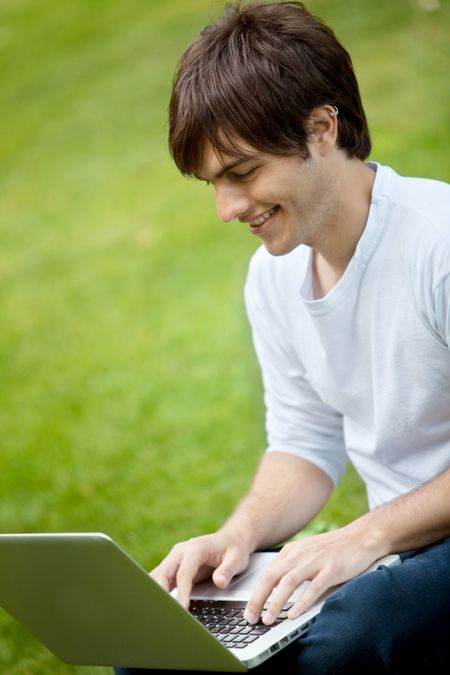 Young man with a laptop outdoors smiling