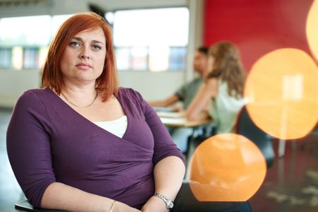 Confident female designer working on a digital tablet in red creative office space