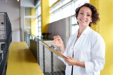 Portrait of a female doctor holding her patient chart in bright modern hospital