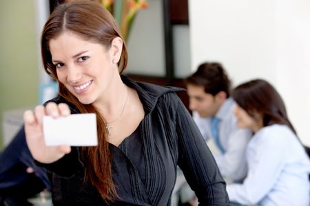 Business woman holding a card smiling at an office