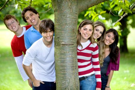 casual group of friends smiling outdoors by a tree