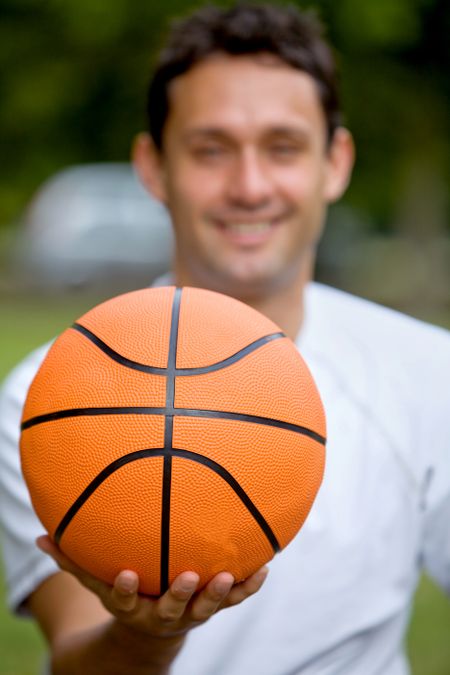 young man with a basketball smiling outdoors