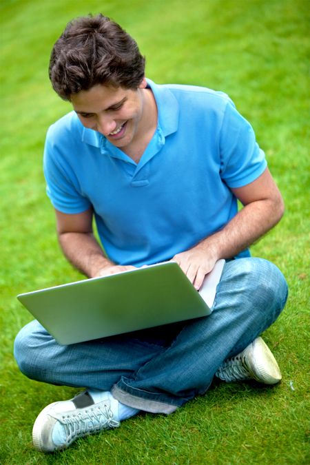 Man working on a laptop outdoors and smiling