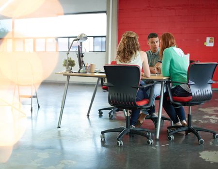 Unposed group of creative business people in an open concept office brainstorming their next project.