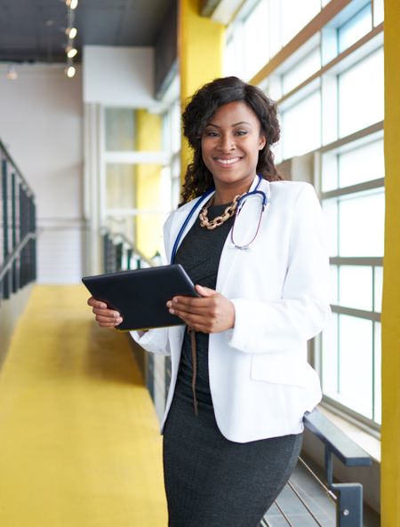 Portrait of a female doctor holding her patient chart on digital tablet in bright modern hospital