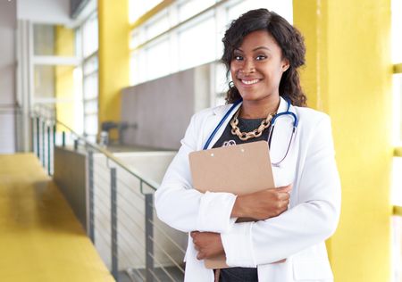 Portrait of a female doctor holding her patient chart in bright modern hospital