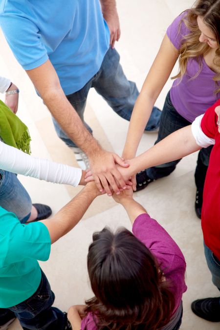 happy group of friends with their hands together in the middle