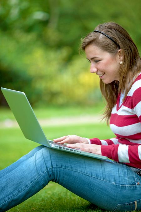 Beautiful happy girl with a computer outdoors