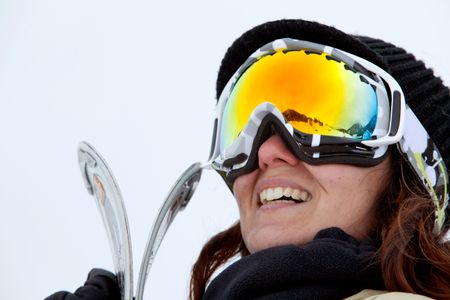female skier with skis smiling and wearing ski glasses