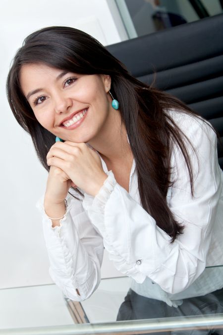 Beautiful business woman in an office leaning on her desk