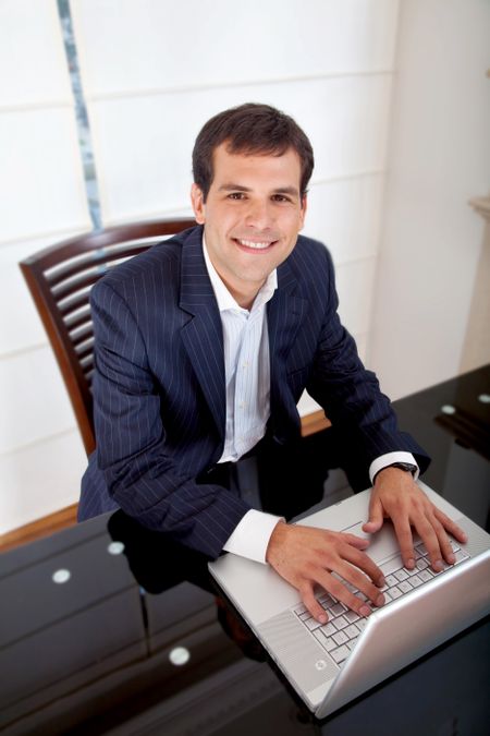 business man looking happy on a laptop in his office